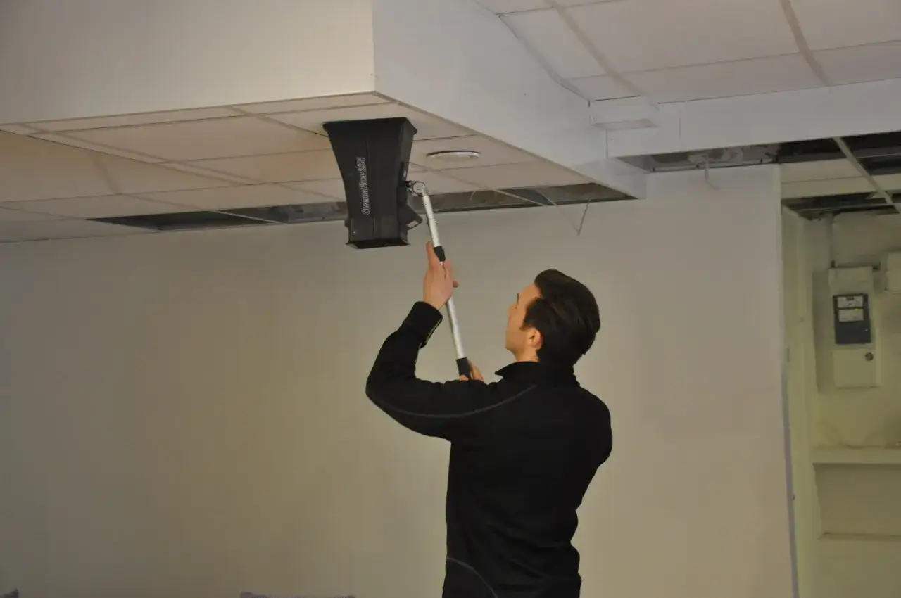 Man utför obligatorisk ventilationskontroll med mätutrustning i taket.