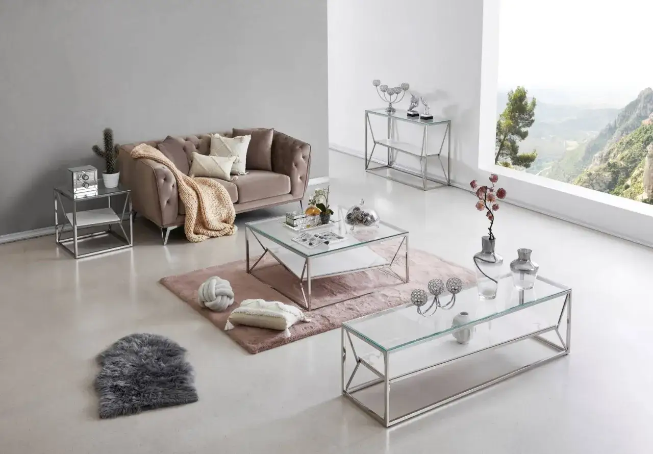 Ett modernt vardagsrum med en sammetssoffa, glasbord och ett elegant avlastningsbord.