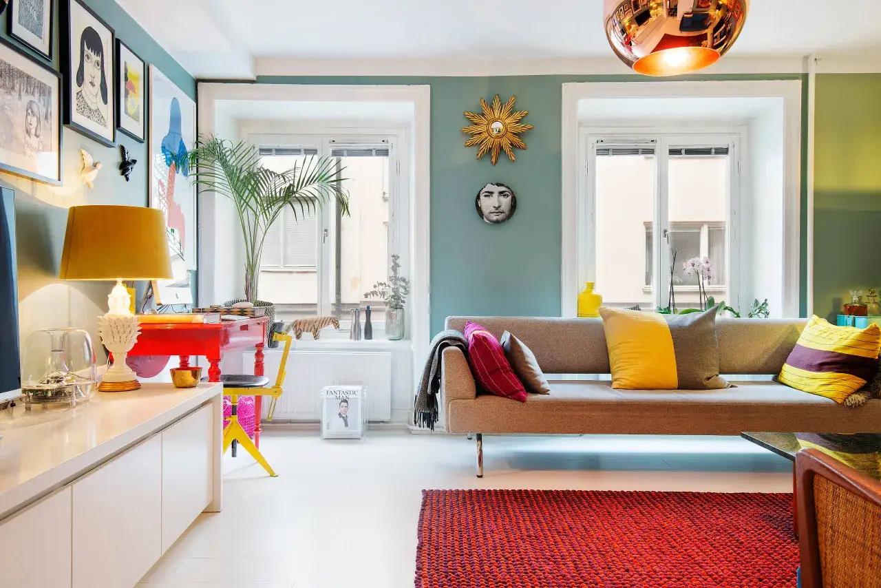 En soffa med färgglada kuddar, en röd byrå och en gul stol skapar en lekfull och modern retro inredning.