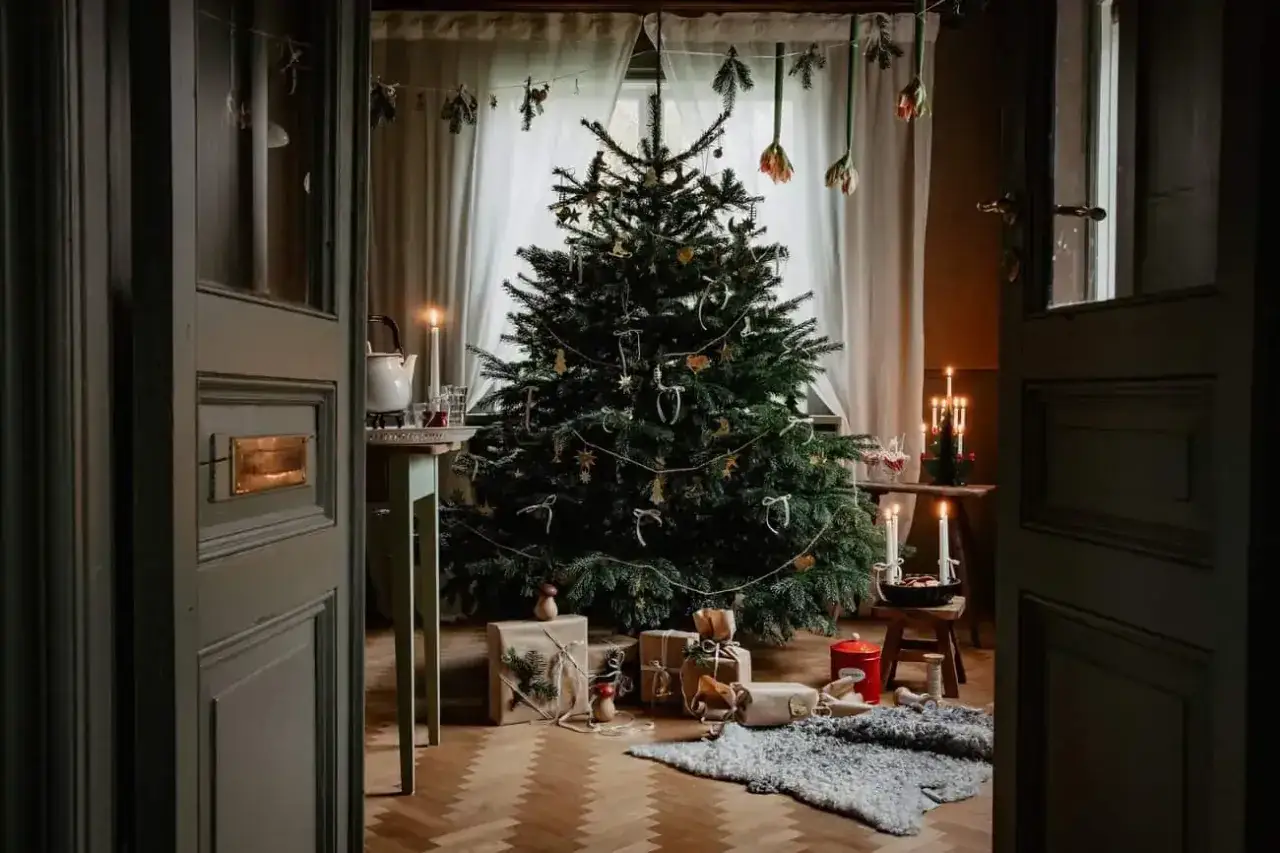 En julgran med stj&auml;rnor och band, omgiven av presenter och levande ljus. Perfekt julpynt inspiration f&ouml;r en mysig jul.