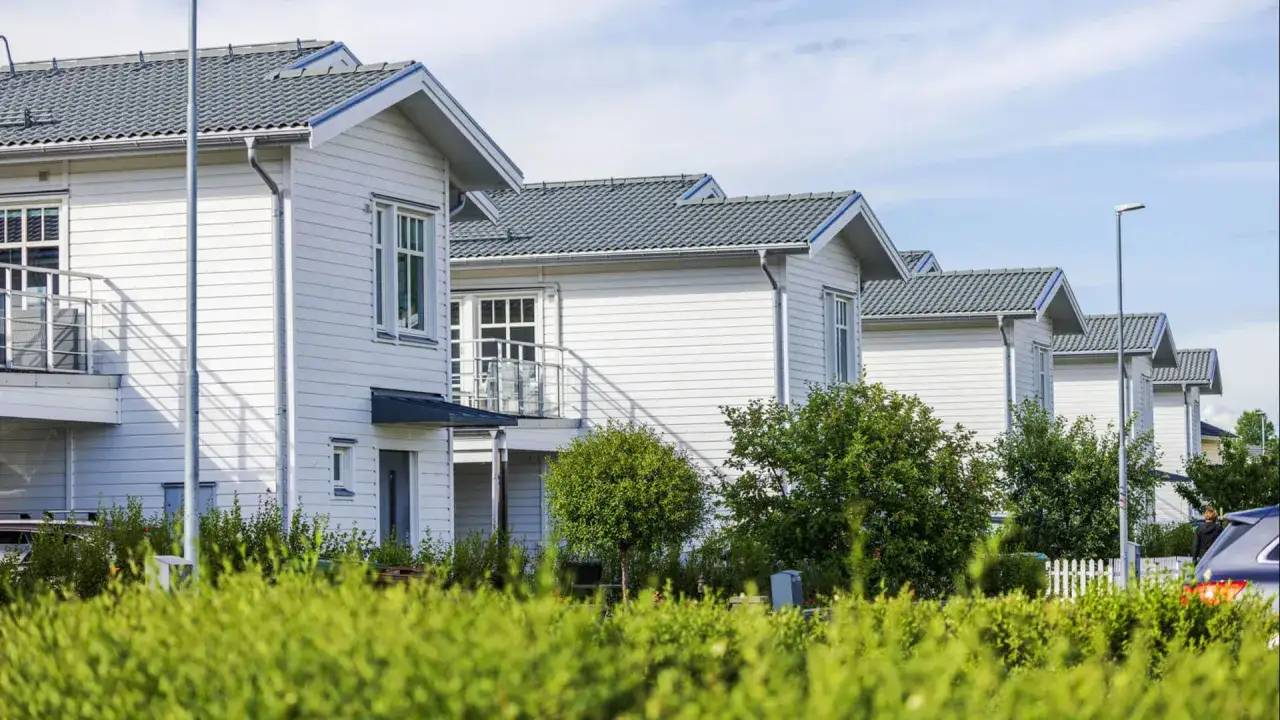Rad av vita tr&auml;hus med gr&aring; tak, en del av en nybyggd villaidyll d&auml;r man kan beh&ouml;va taxera om fastighet.