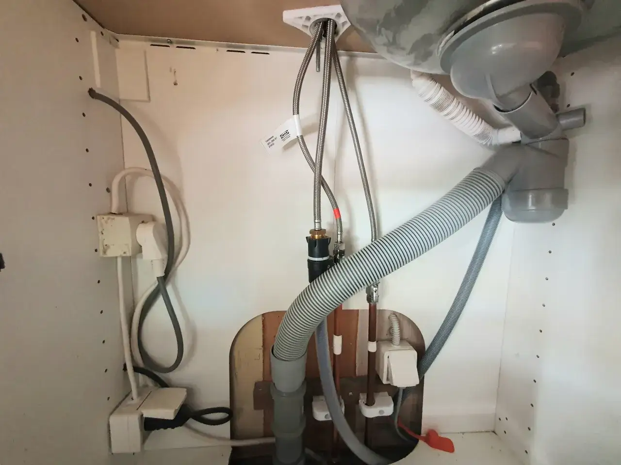 Under diskb&auml;nken syns r&ouml;rdragning f&ouml;r diskmaskin, inklusive vattenanslutning och avlopp. Kranen till diskmaskinen &auml;r p&aring; eller av.