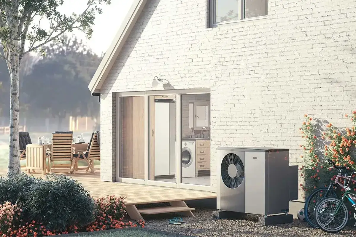 Nibe S2125-12 värmepump står bredvid ett modernt hus med altan och trädgårdsmöbler.