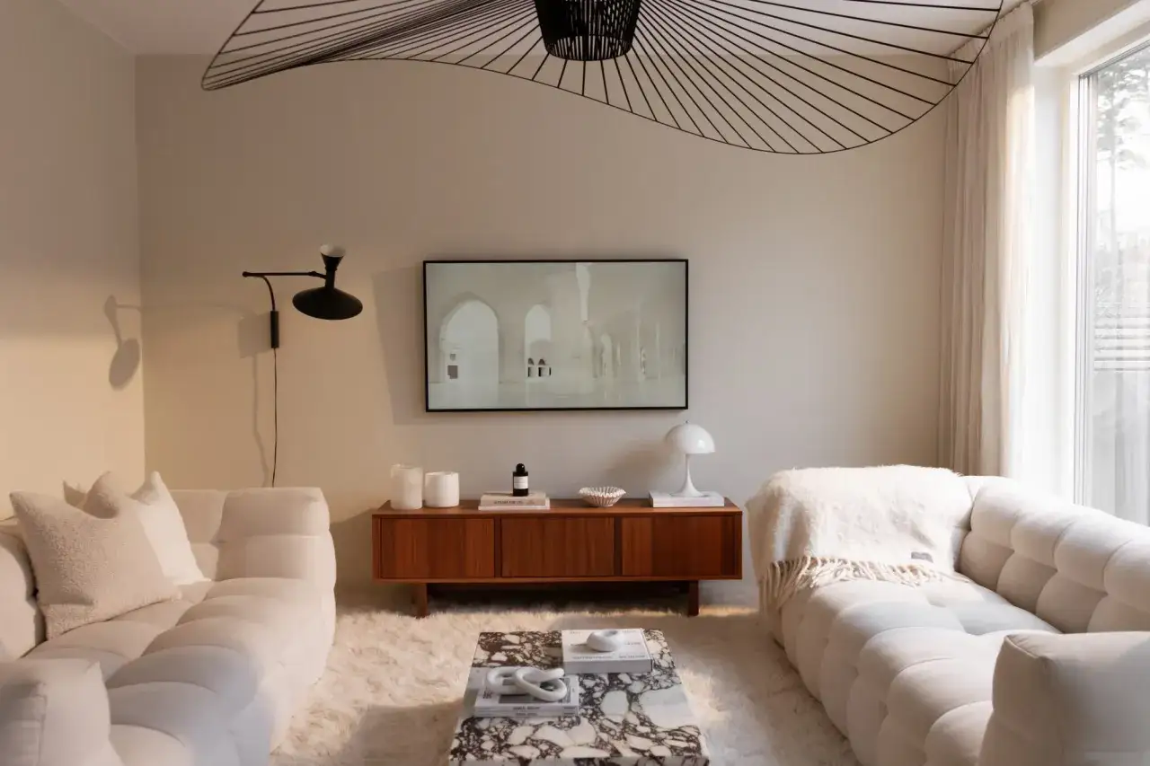 Mysigt tvrum inspiration med vita soffor, marmorbord och en teakmöbel. En stor taklampa ger rummet karaktär.