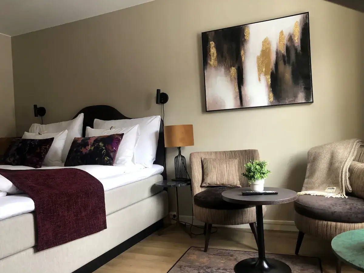 Mysig hotellrum inredning med stor s&auml;ng, bekv&auml;ma f&aring;t&ouml;ljer och modern konst.