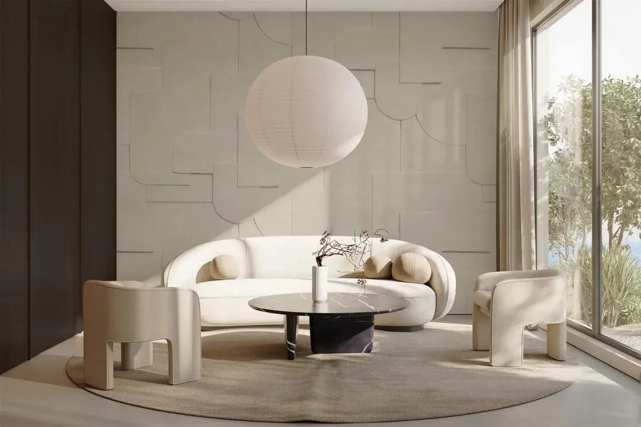 Ett ljust vardagsrum med en rund soffa, tv&aring; f&aring;t&ouml;ljer och ett marmorbord. En stor papperslampa h&auml;nger fr&aring;n taket. Rummet har en minimalistisk design med en texturerad v&auml;gg.