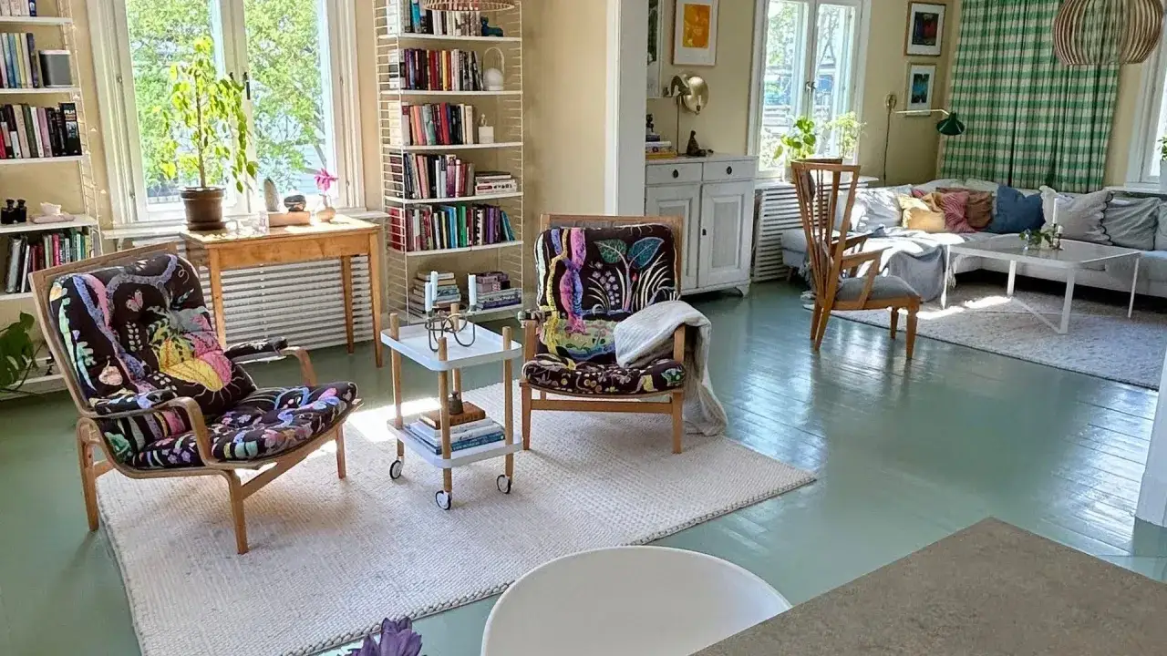 Tv&aring; f&aring;t&ouml;ljer med f&auml;rgglada m&ouml;nster, en bokhylla och en soffgrupp i ett ljust rum. Styling hem.