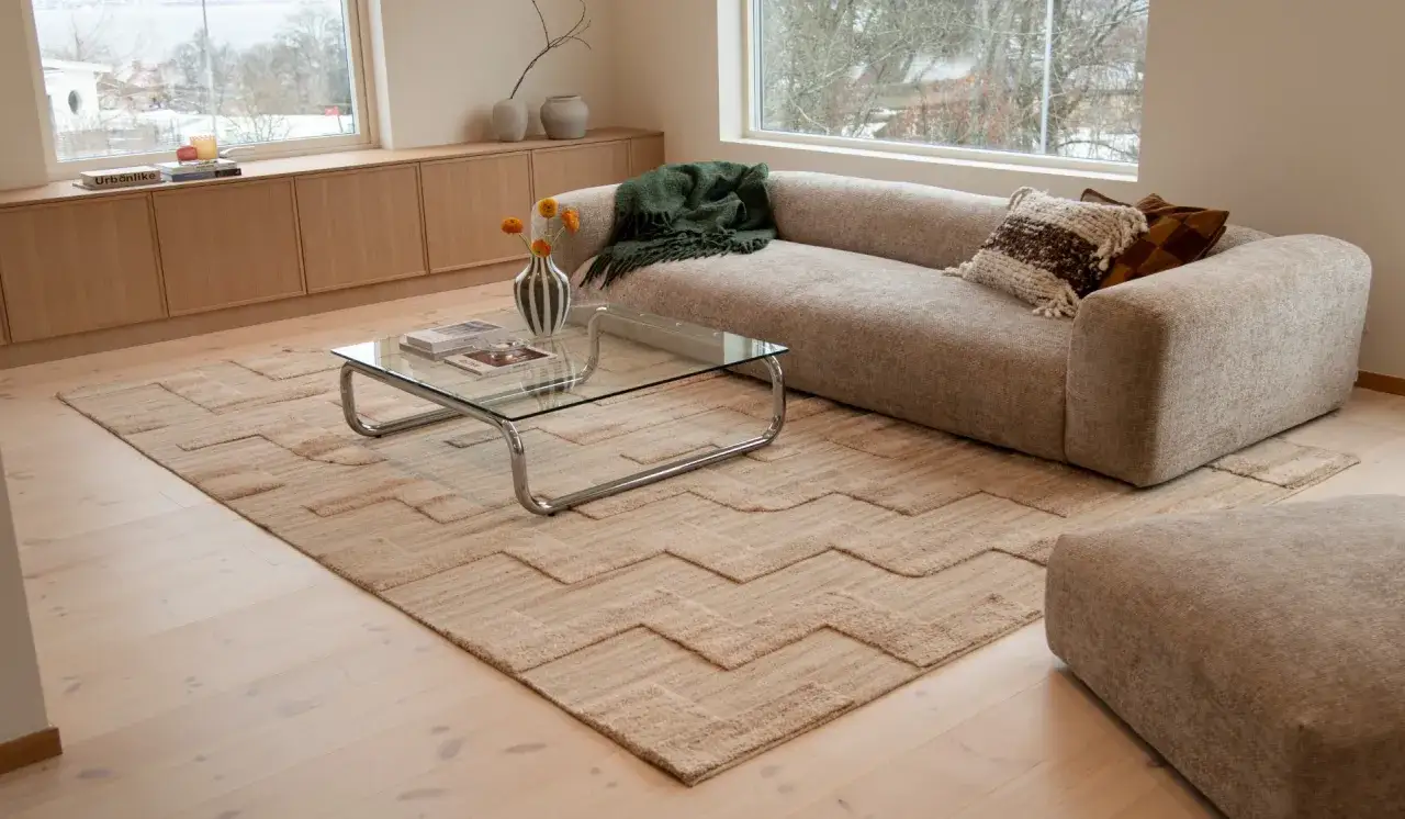 En mysig soffgrupp med flera mattor i samma rum. En stor, m&ouml;nstrad matta t&auml;cker golvet framf&ouml;r soffan och ett mindre exemplar ligger under soffbordet.
