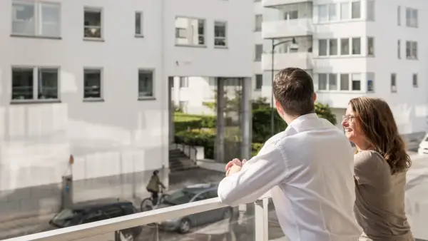 Ett par njuter av utsikten från sin balkong, kanske funderar på framtida medlemsinsatser brf.
