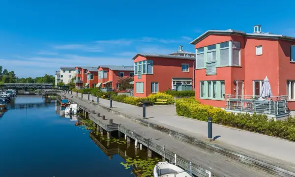 Radhus vid vattnet med båtar i hamnen. En extern styrelse för brf kan diskutera kostnad för underhåll av bryggan.