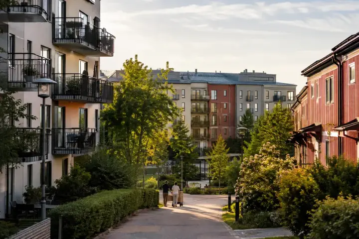 Två personer flyttar kartonger på en gångväg i ett modernt bostadsområde. Kanske redo att hyra ut i andra hand?
