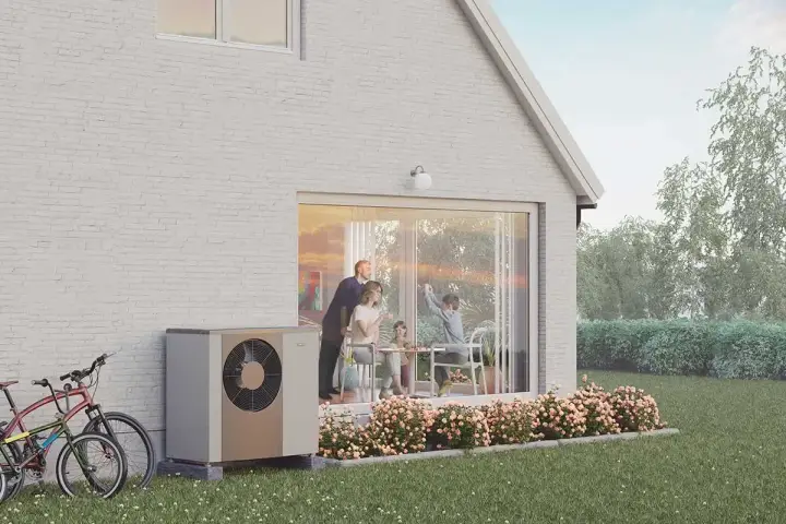 En familj njuter av en solig dag vid sitt hus, med en NIBE S2125-12 värmepump som diskret står vid sidan.